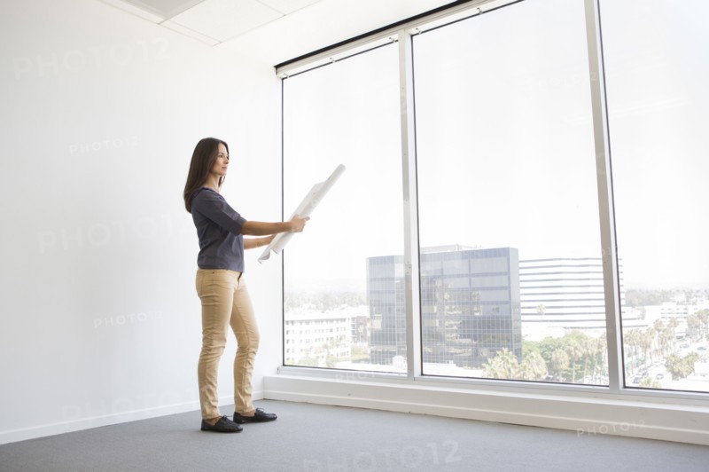 Woman reading blueprints in empty office