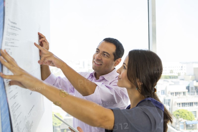 Business people examining blueprints in office