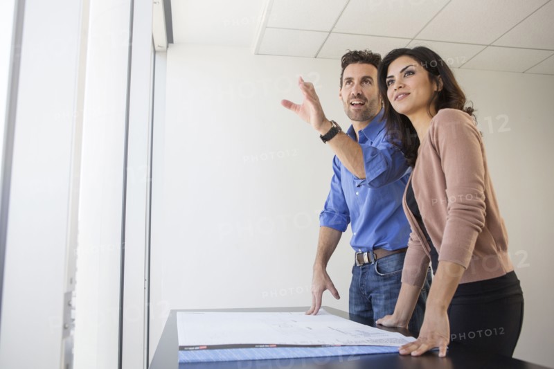 Business people examining blueprints in office