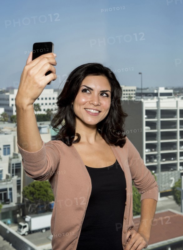 Mixed race businesswoman taking cell phone picture