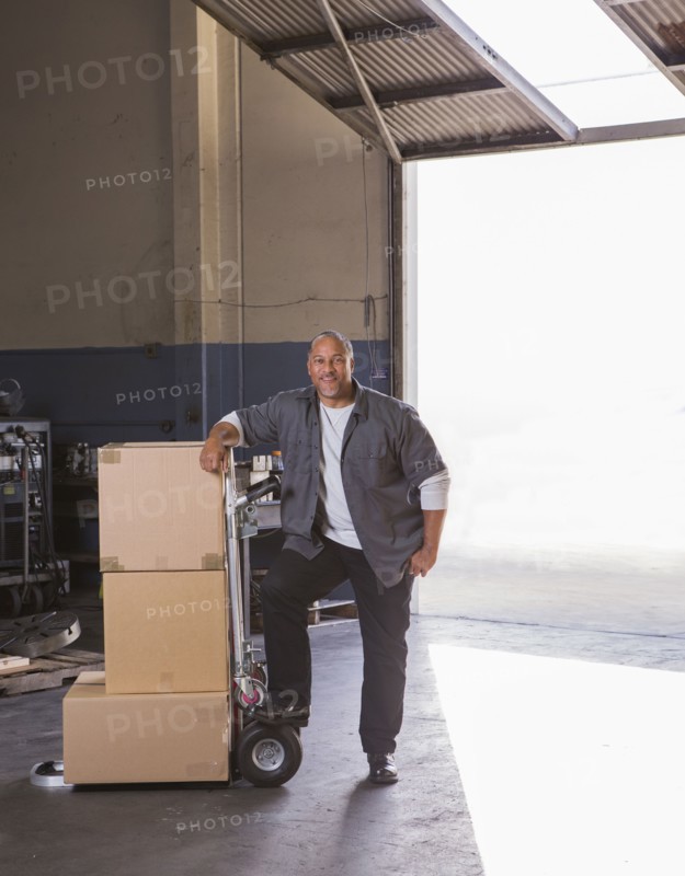 Worker with boxes on hand truck in warehouse