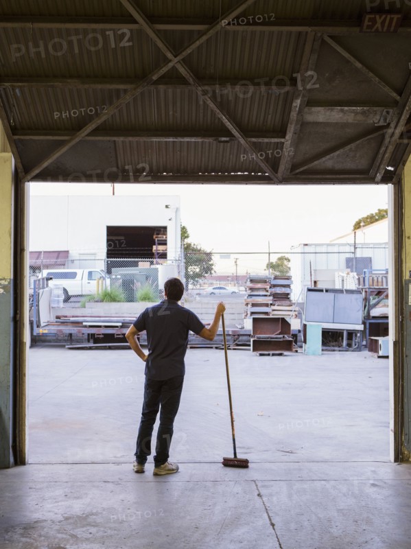 Worker holding broom in warehouse