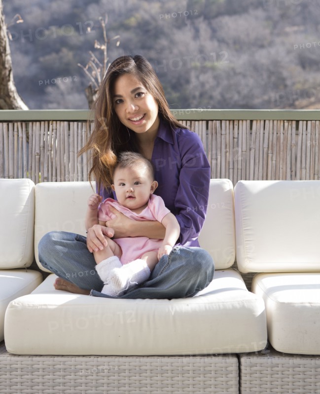 Mother holding baby girl on patio sofa