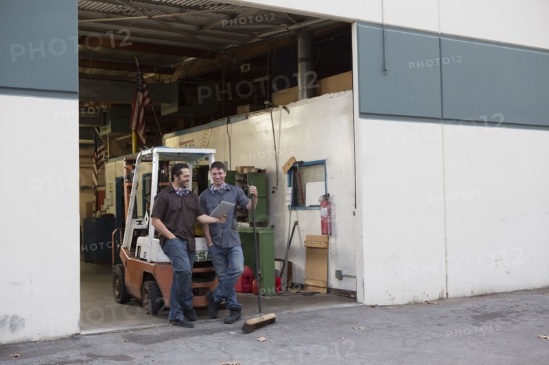 Workers using digital tablet at warehouse loading dock