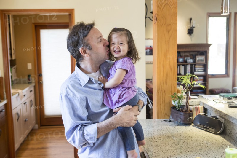 Father kissing daughter in kitchen