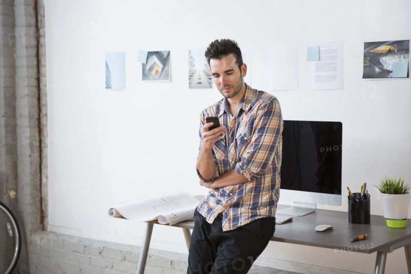 Caucasian architect using cell phone in office