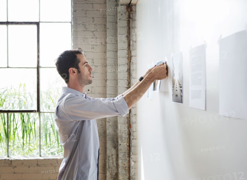 Caucasian architect hanging photos in office