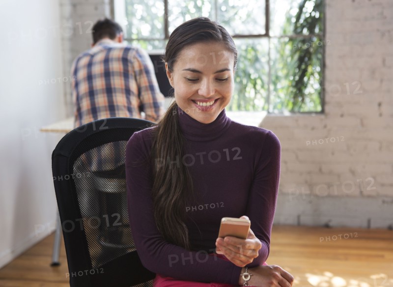 Mixed race architect using cell phone in office