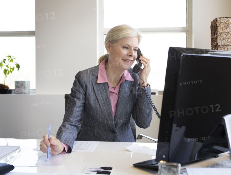 Caucasian businesswoman talking on phone at desk