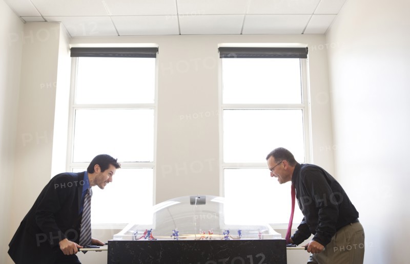 Businessmen playing foosball together in office