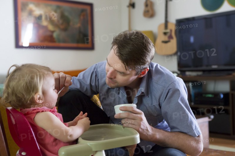 Caucasian father feeding toddler daughter