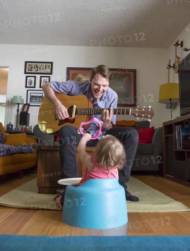 Caucasian father playing guitar for daughter
