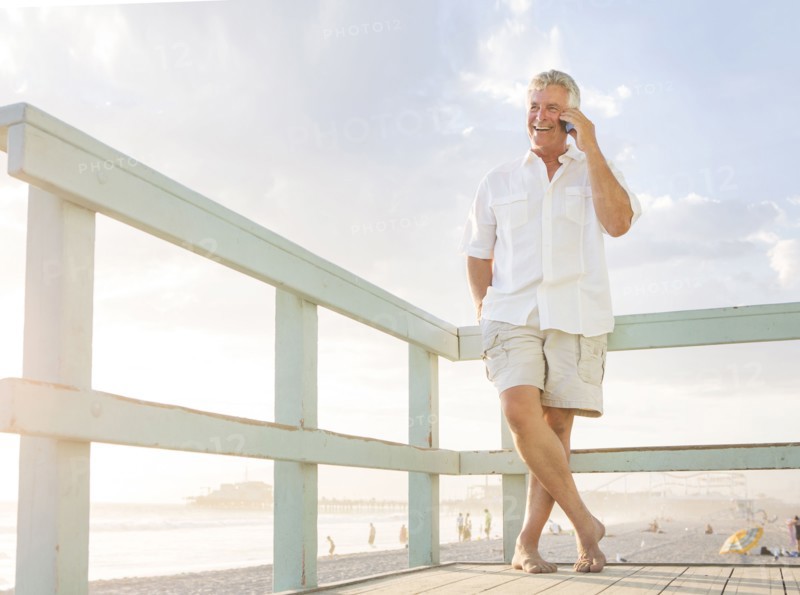 Caucasian man talking on cell phone on boardwalk at beach