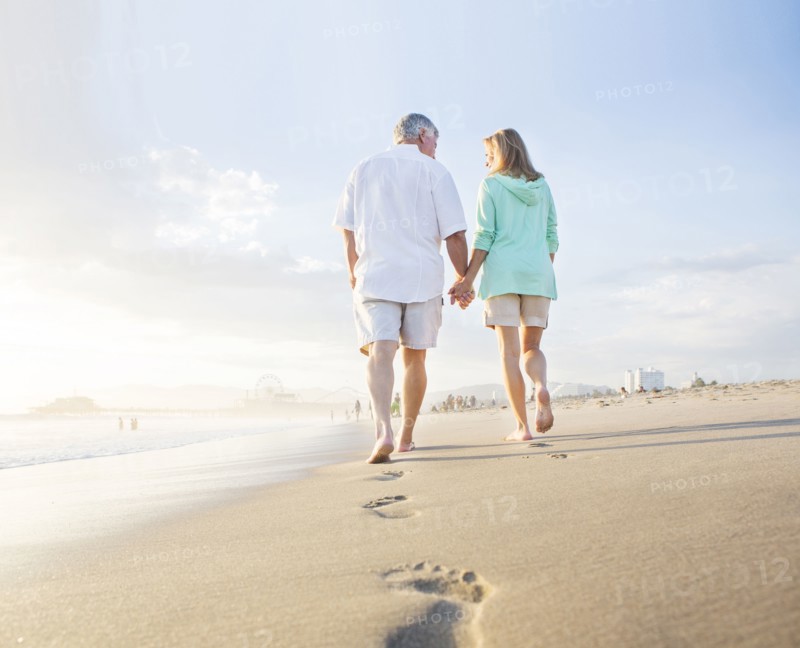 Caucasian couple leaving footprints on beach