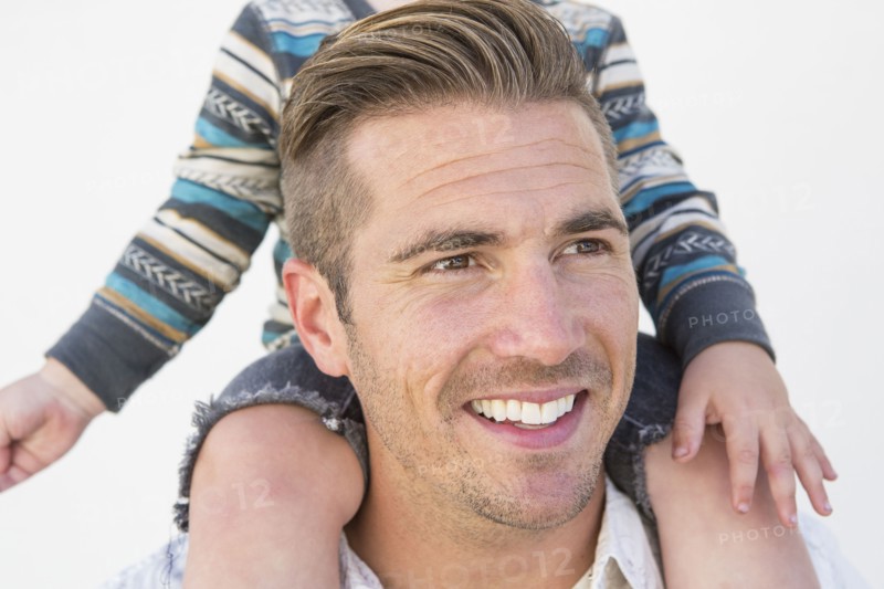 Close up of Caucasian father holding son on shoulders