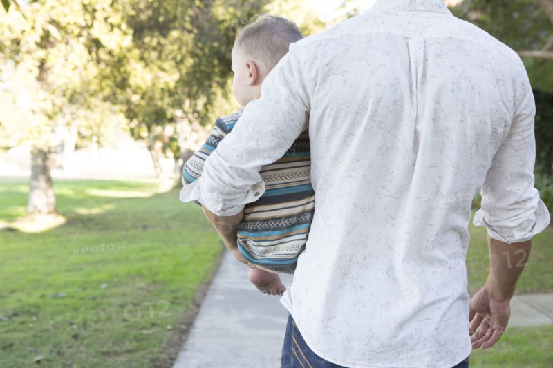 Caucasian father carrying son on sidewalk