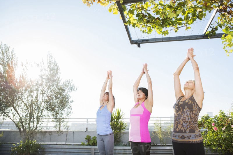 Women practicing yoga together on urban rooftop