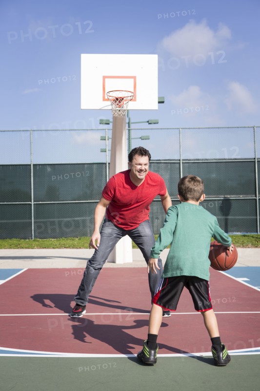 Caucasian father and son playing on basketball court
