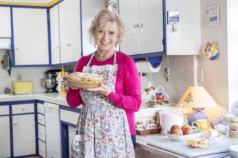 Older Caucasian woman baking pie in kitchen