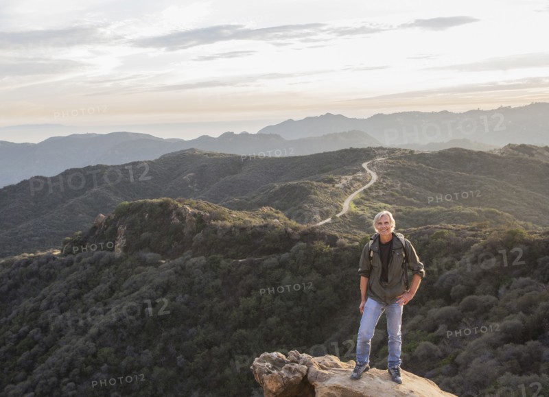 Older Caucasian man standing on rocky hilltop