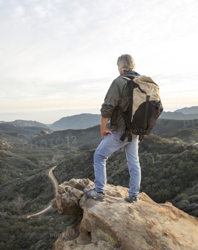 Older Caucasian man standing on rocky hilltop