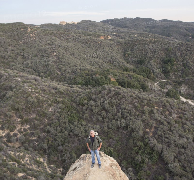 High angle view of older Caucasian man standing on rocky hilltop