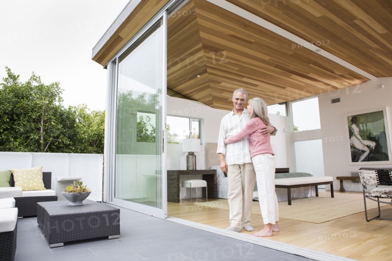 Older Caucasian couple hugging on porch