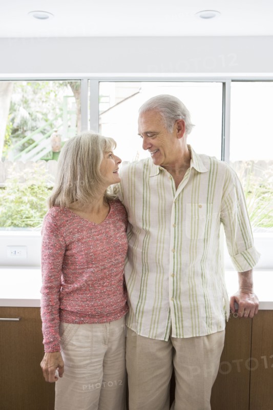 Older Caucasian couple hugging in kitchen