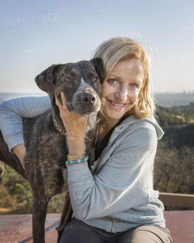 Caucasian woman hugging dog on hilltop