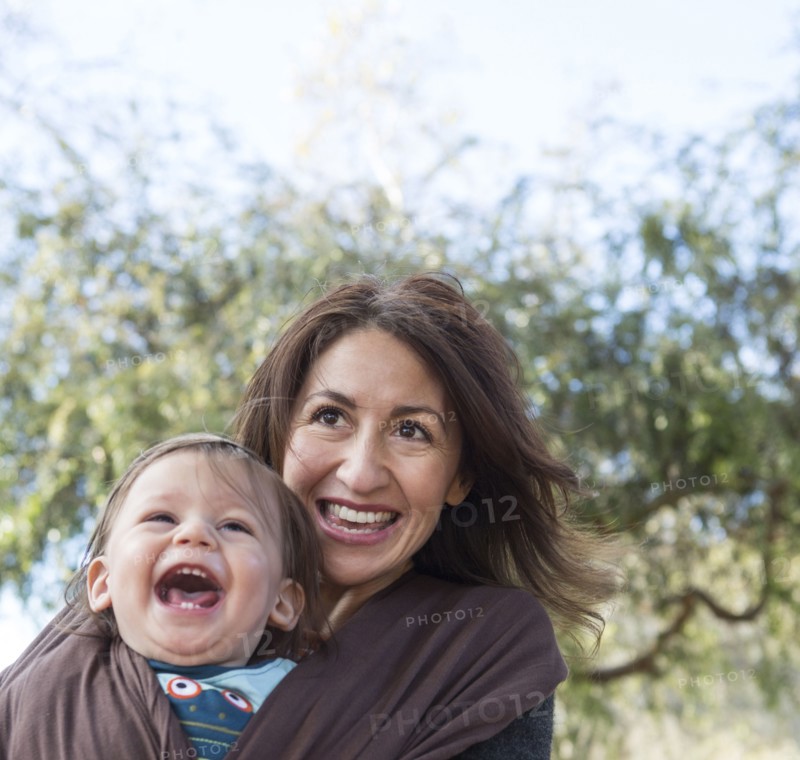 Hispanic mother wearing son in carrier outdoors