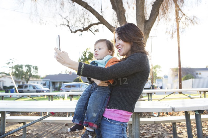 Hispanic mother taking selfie with son in park