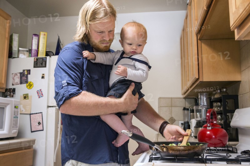 Caucasian father holding son and cooking