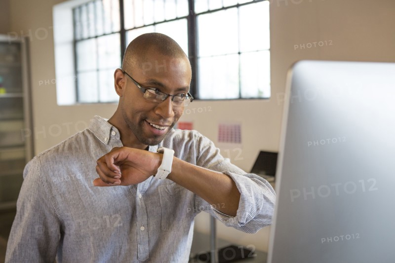 Mixed race businessman talking into smart watch in office