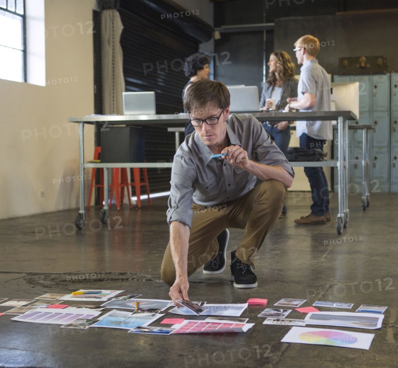 Caucasian businessman examining paperwork on office floor