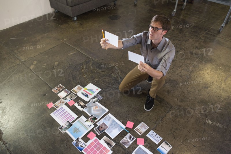 Caucasian businessman examining paperwork on office floor