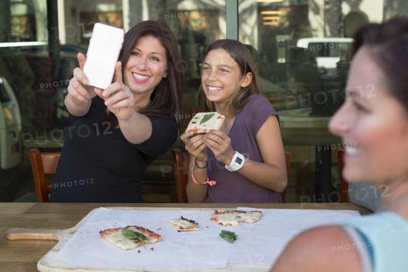 Mother and daughter taking selfie in cafe