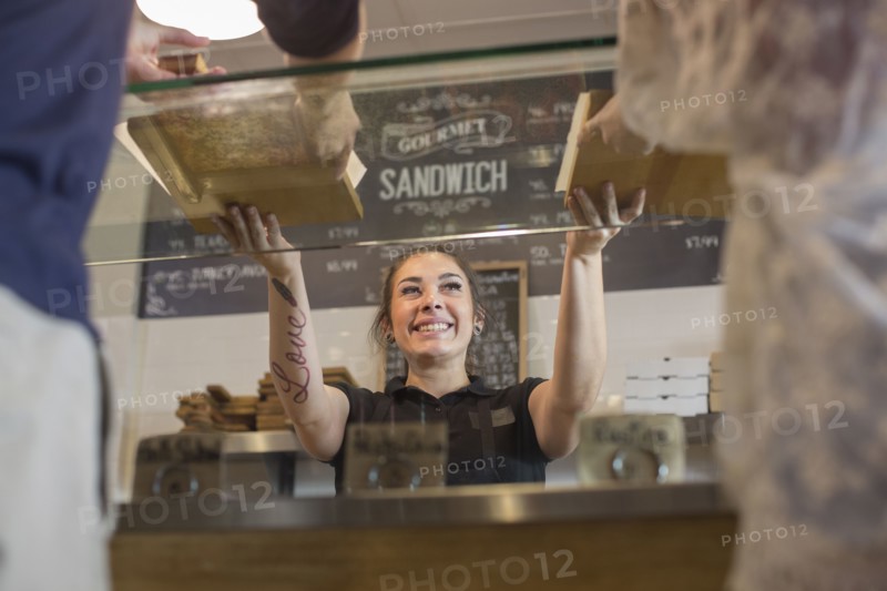 Server handing pizza to customers in cafe