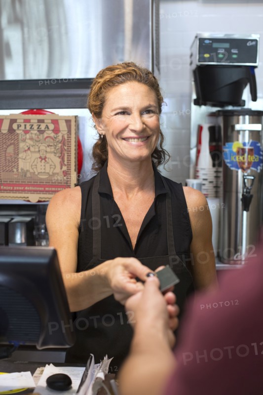 Server helping customer purchase pizza in cafe