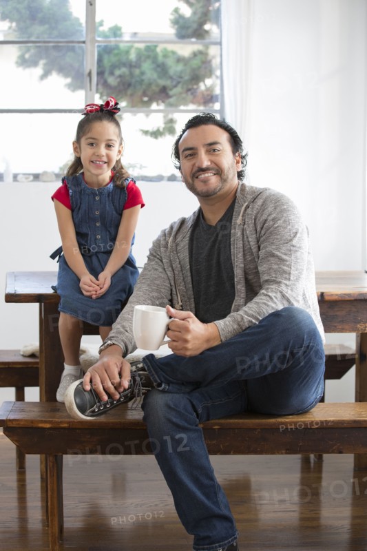 Hispanic father and daughter smiling at table