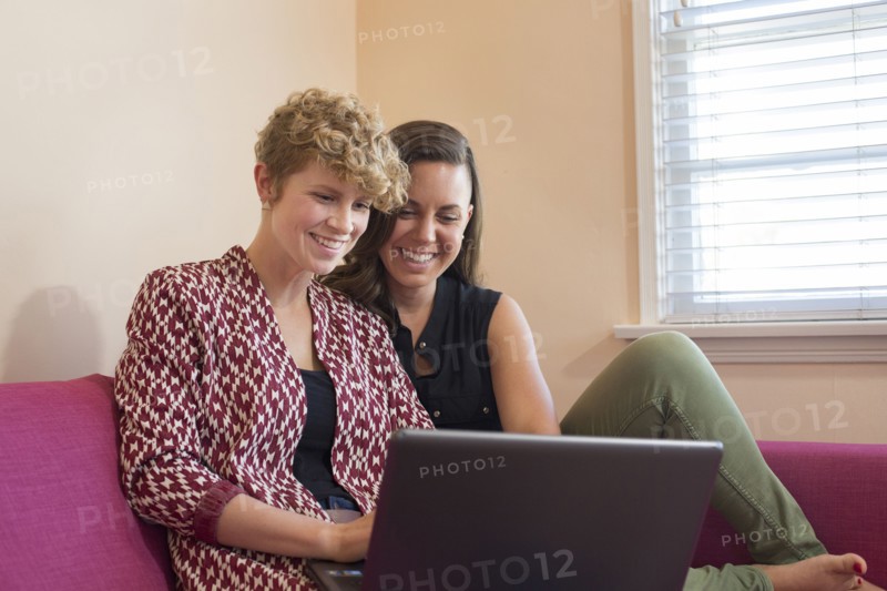 Caucasian lesbian couple using laptop on sofa