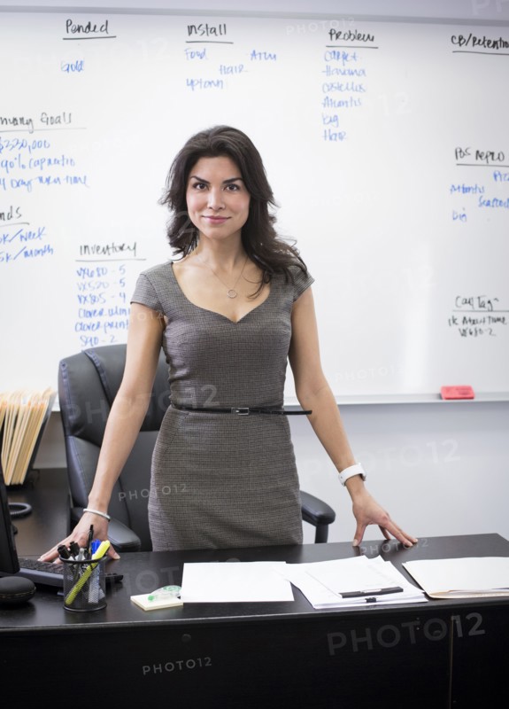 Mixed race businesswoman standing at desk in office