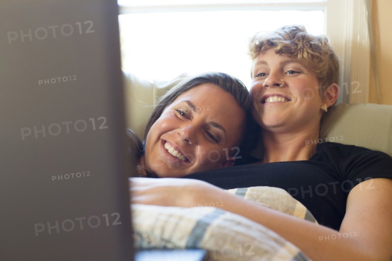 Caucasian lesbian couple cuddling in bed