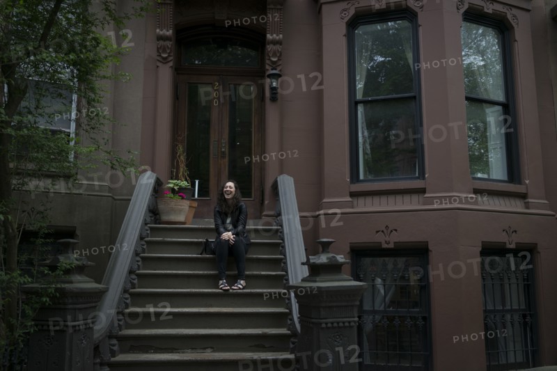 Caucasian woman sitting on townhouse front stoop