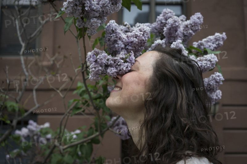 Caucasian woman smelling flowers on city street