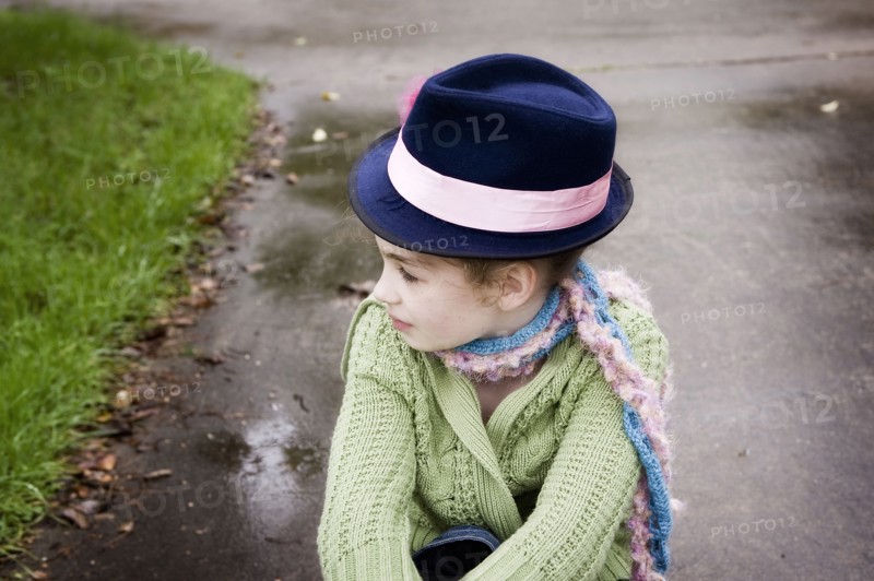 Caucasian girl wearing fedora hat on rainy concrete
