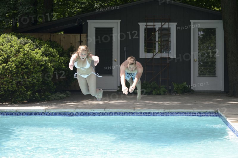 Couple diving into swimming pool in backyard