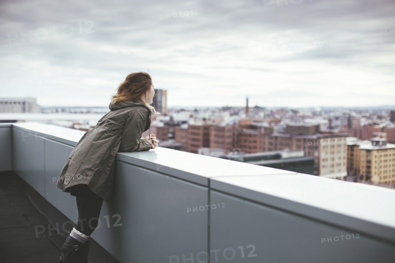 Caucasian woman on urban rooftop admiring cityscape