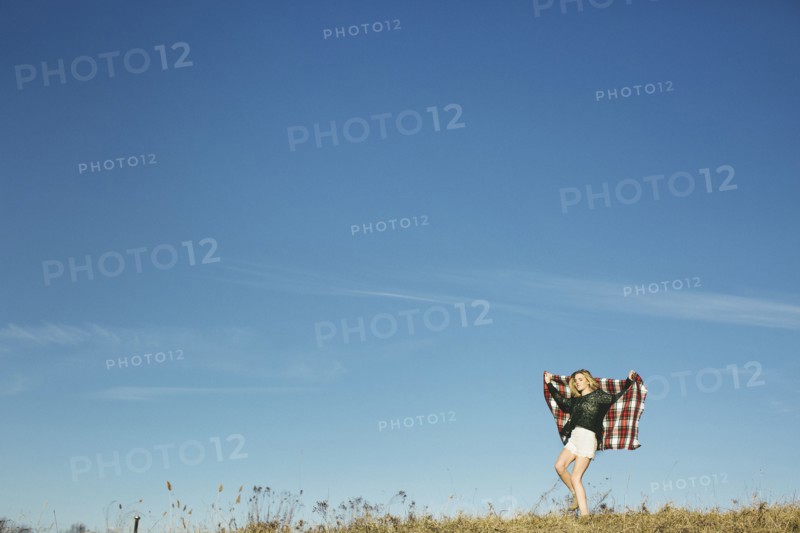 Caucasian woman playing with scarf on hilltop