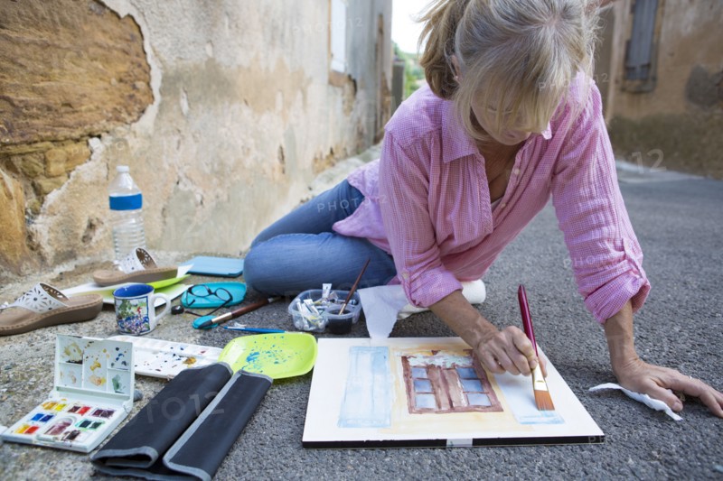 Caucasian woman painting on concrete ground