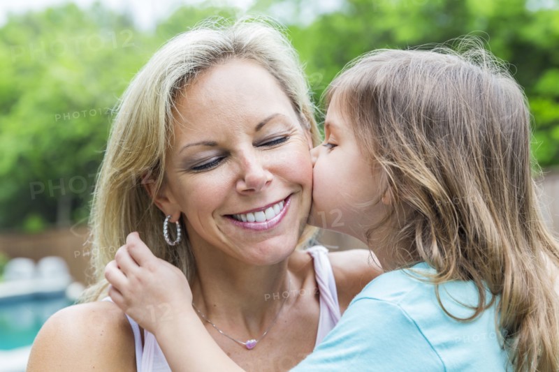 Caucasian girl kissing mother in backyard